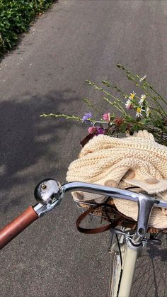 a bicycle parked on the side of a road next to flowers and a basket filled with blankets