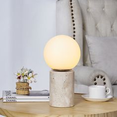 a table with a lamp on top of it next to a chair and coffee cup