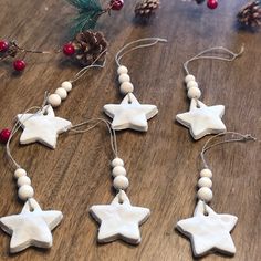 christmas decorations made out of clay stars and beads on a wooden table with pine cones