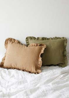 two pillows sitting on top of a bed next to each other in front of a white wall