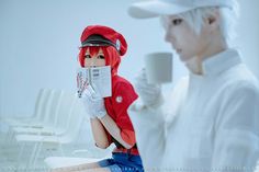 two people dressed in white and red, one holding a newspaper while the other holds a cup