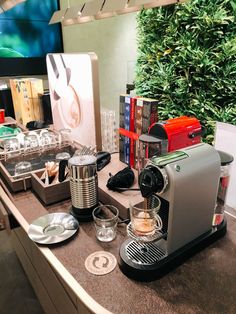 an espresso machine sitting on top of a counter next to plates and cups