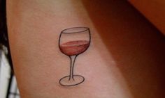 a woman's arm with a small tattoo of a wine glass on the side