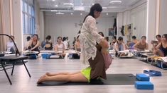 a woman sitting on top of a yoga mat in front of a group of people