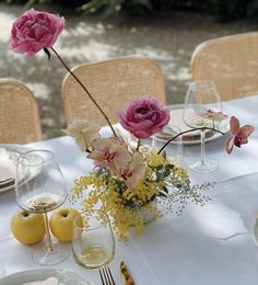 the table is set with flowers and wine glasses on it, along with plates and utensils