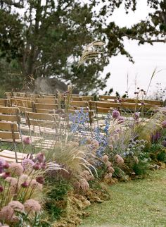 a row of wooden benches sitting next to each other on top of a lush green field