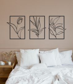 three black and white paintings on the wall above a bed