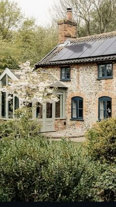 an old brick house with solar panels on the roof and windows in front of it