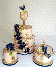 three tiered wedding cake with blue flowers and gold trimmings on the sides