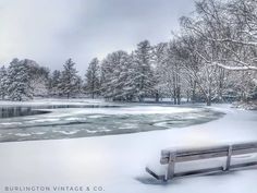 a park bench sitting in the snow near a lake