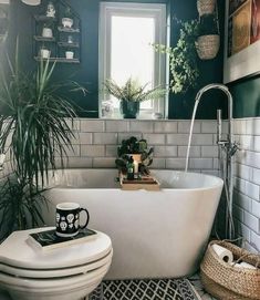 a bathroom with a white tub, toilet and plants on the counter top in front of it