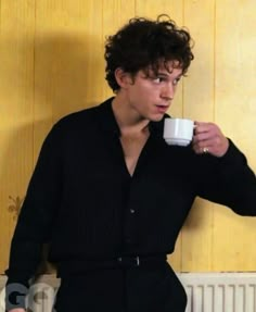 a young man holding a coffee cup in his right hand