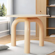 a round table in the middle of a living room with bookshelves behind it