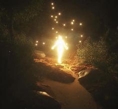 a person standing in the middle of a path lit up with lights at night time