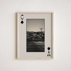 a black and white photo hanging on the wall next to a playing card with two hearts