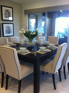 a dining room table with white chairs and plates