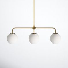 three white balls hanging from a brass chandelier with four lights on each end