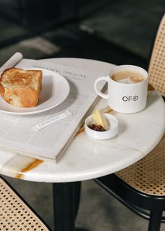 a plate with bread and butter on it next to a cup of coffee sitting on a table