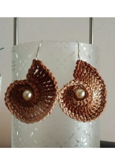 two brown crocheted earrings with pearls hanging from them