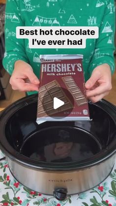 a person holding a box of hershey's chocolate in front of a slow cooker