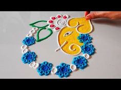 someone is making an intricate rang work on the surface with beads and flowers in blue, yellow and white colors