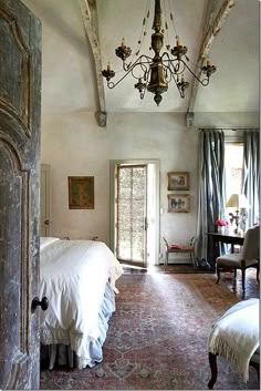 a bedroom with a chandelier hanging from the ceiling and an open door leading to another room