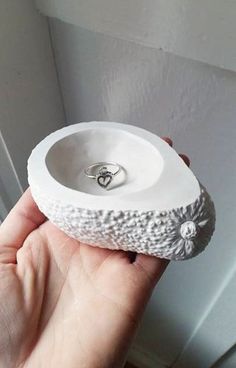 a hand holding a white ring dish in front of a door