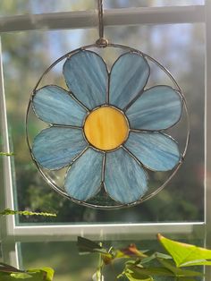 a stained glass sun catcher with a blue flower on it's center and yellow center