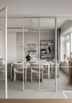 a dining room with glass walls and white furniture