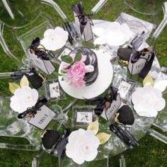 a table topped with a cake and flowers on top of plastic chairs in the grass