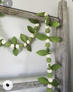 some green leaves and white balls hanging from a wooden frame