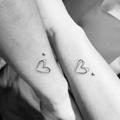 two people holding hands with tattoos on their arms, one has a heart and the other has