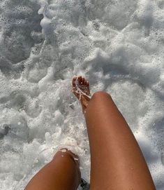 a person's feet in the water with white foam on them and one foot sticking out