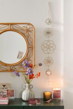 there is a mirror on the wall next to a dresser with flowers and candles in it