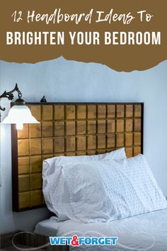 a bed with white sheets and brown headboard next to a light on the wall