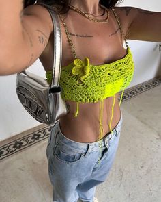 a woman wearing a yellow top and jeans is taking a selfie with her cell phone