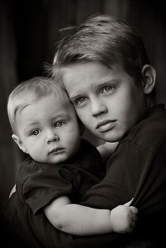 two young boys hugging each other in black and white