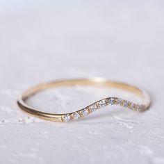 a yellow gold wedding band with diamonds on it's side, sitting on a white surface