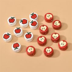 several red and white apples with faces on them sitting next to each other in front of a beige background