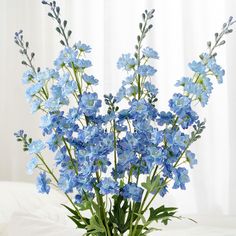 blue flowers are in a vase on a bed