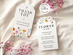 two tags that say thank you and have flowers in them on a white bed sheet