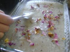 a person is spooning some food out of a glass dish with pink flowers on it