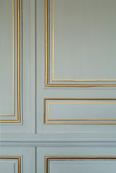 a teddy bear sitting on top of a bed in front of a blue door with gold trim