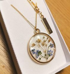 a necklace with flowers on it sitting in a box