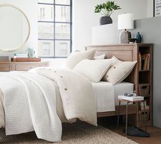 a bed with white sheets and pillows in a bedroom