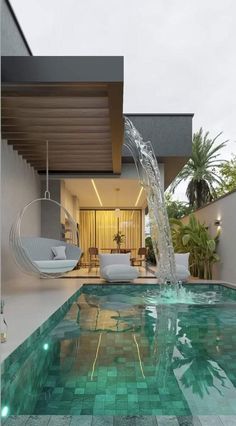 an indoor swimming pool with water running from the ceiling to the floor and furniture around it