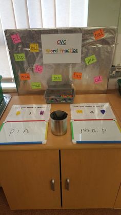 a wooden table topped with lots of magnets next to a metal pot filled with writing