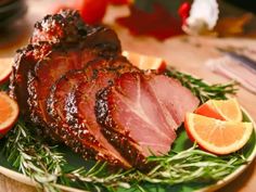 sliced ham on a plate with oranges and herbs