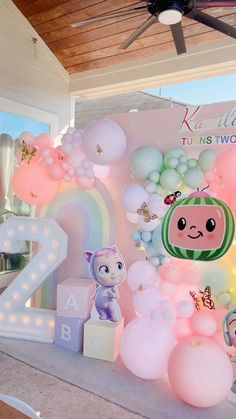 there are balloons and toys on the table in front of the number two sign that says it's 2