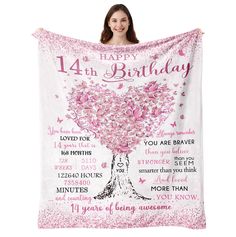 a woman holding up a pink birthday blanket